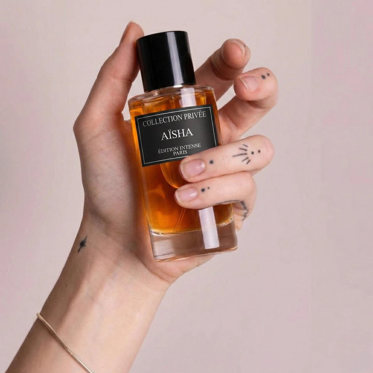 Eine Hand hält den luxuriösen, orangefarbenen Flakon des Aïsha Parfüms vor einem ästhetischen, neutralen Hintergrund.