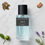 Der minimalistische Glasflakon von Collection Privée Aqua mit hellblauer Flüssigkeit, umgeben von frischem Zitrus, Lavendelzweigen, Rosmarin und edlem Holz auf hellem Marmor.