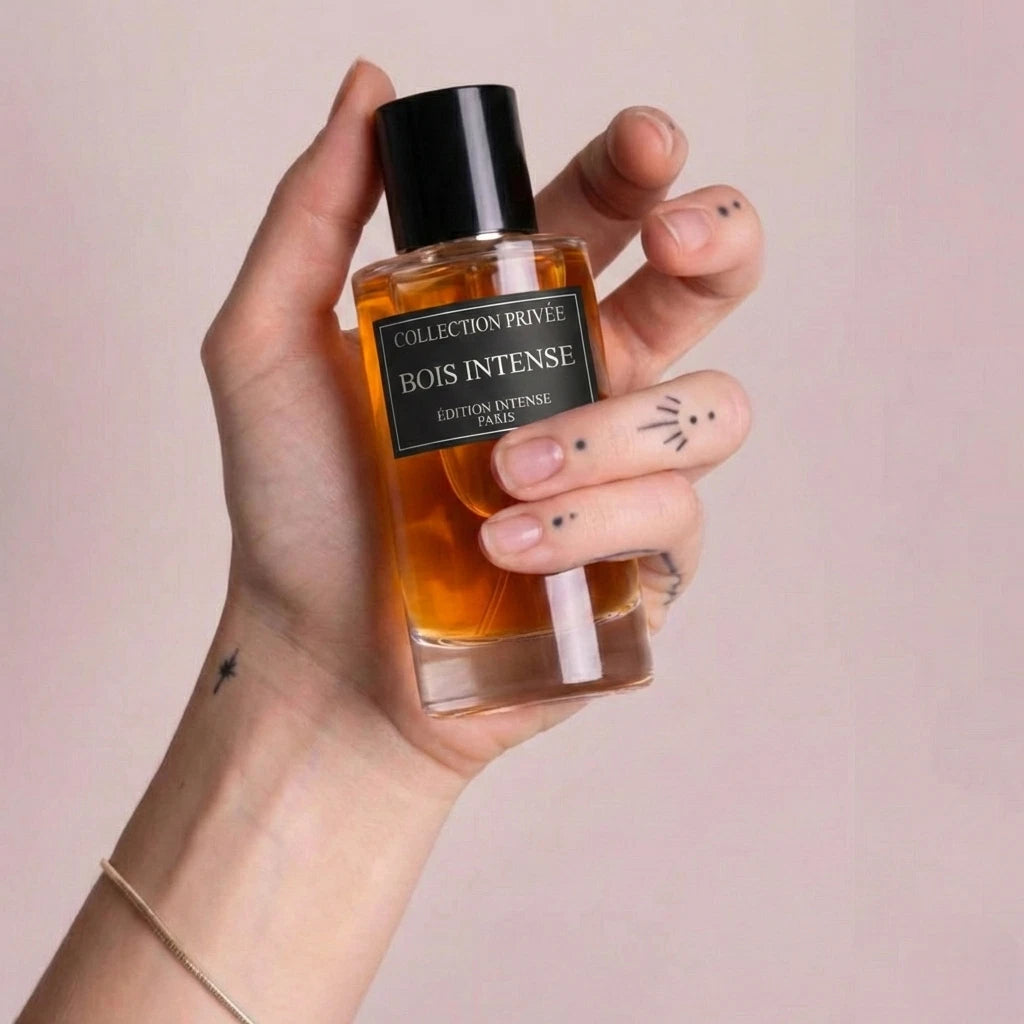 Der minimalistische Flakon von Bois Intense, stilvoll präsentiert in einer Hand vor einem sanften, rosafarbenen Hintergrund.