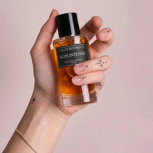Der minimalistische Flakon von Bois Intense, stilvoll präsentiert in einer Hand vor einem sanften, rosafarbenen Hintergrund.