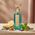 Der türkisfarbene Glasflakon des Emir Celestial Parfüms mit goldenem Flügel-Verschluss, elegant arrangiert mit Zitrone, Lavendel, Zimtstangen und Harz.