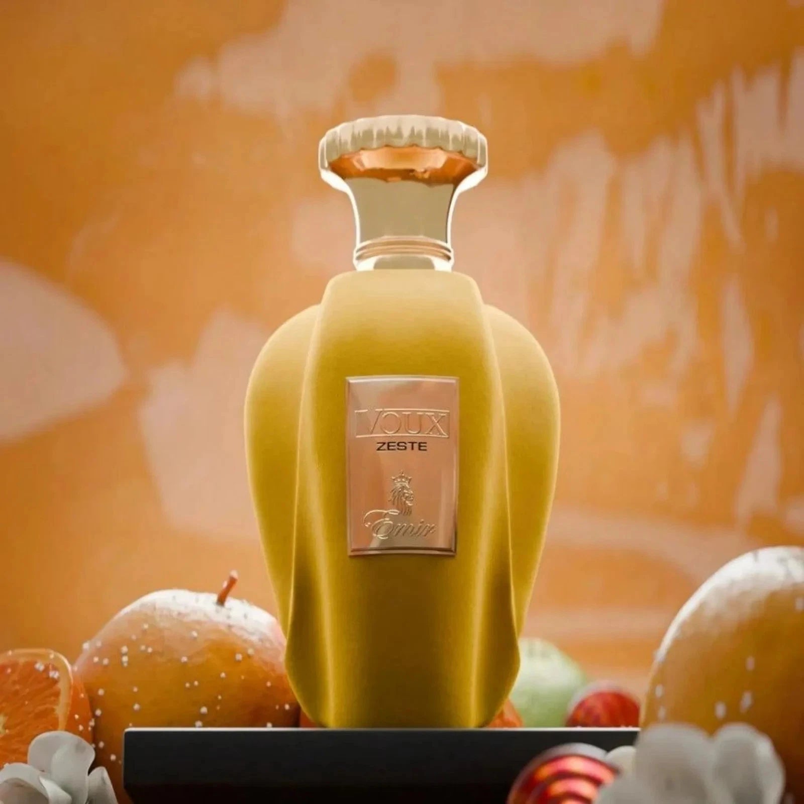 Der samtige, gelbe Glasflakon des Emir Voux Zeste Eau de Parfum für Damen, luxuriös präsentiert vor einem warmen, pfirsichfarbenen Hintergrund.