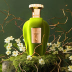 Der samtig hellgrüne Glasflakon des Emir Voux Zingy Eau de Parfum, natürlich und elegant inszeniert auf einem moosigen Untergrund mit zarten weißen Blüten.
