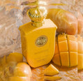 Der leuchtend gelbe Flakon von Gulf Orchid Mango Ice mit goldener Krone, erfrischend umgeben von frischen Mangostücken und Eiswürfeln.