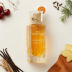 Der edle, goldene Glasflakon von Gulf Orchid Old Fashioned mit Orangenscheibe am Deckel, stilvoll arrangiert mit frischen Kirschen, Ingwer, Zimtnelken und Leder.