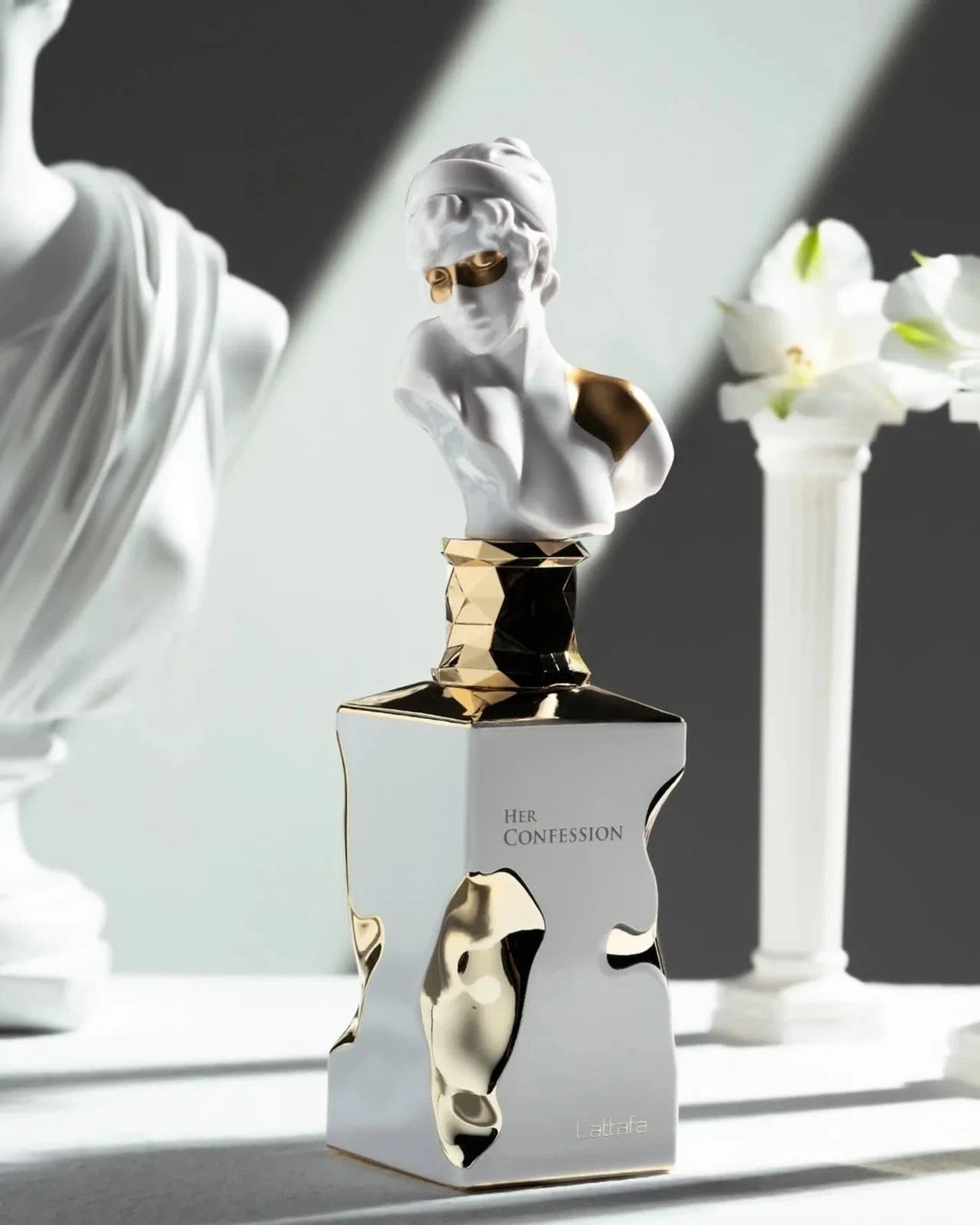 Stilvolle und künstlerische Präsentation des Her Confession Flakons in einer hellen Umgebung mit klassischen weißen Statuen im Hintergrund.