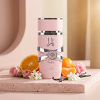Stilvolle Präsentation des Lattafa Yara Pink Flakons auf einem hellen Steinpodest, dekoriert mit frischen Orangen und Blüten in einer weichen, sonnigen Atmosphäre.